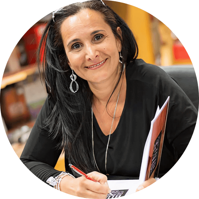 Woman sitting at a desk with a pen and paper, smiling.
