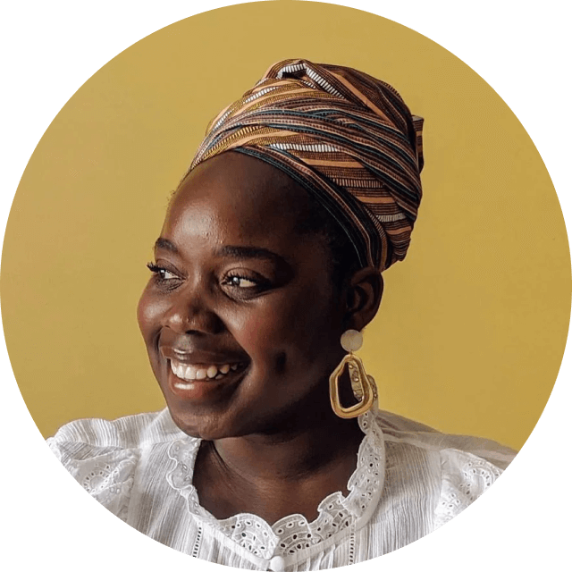 Woman wearing a patterned headscarf and gold earrings against a yellow background